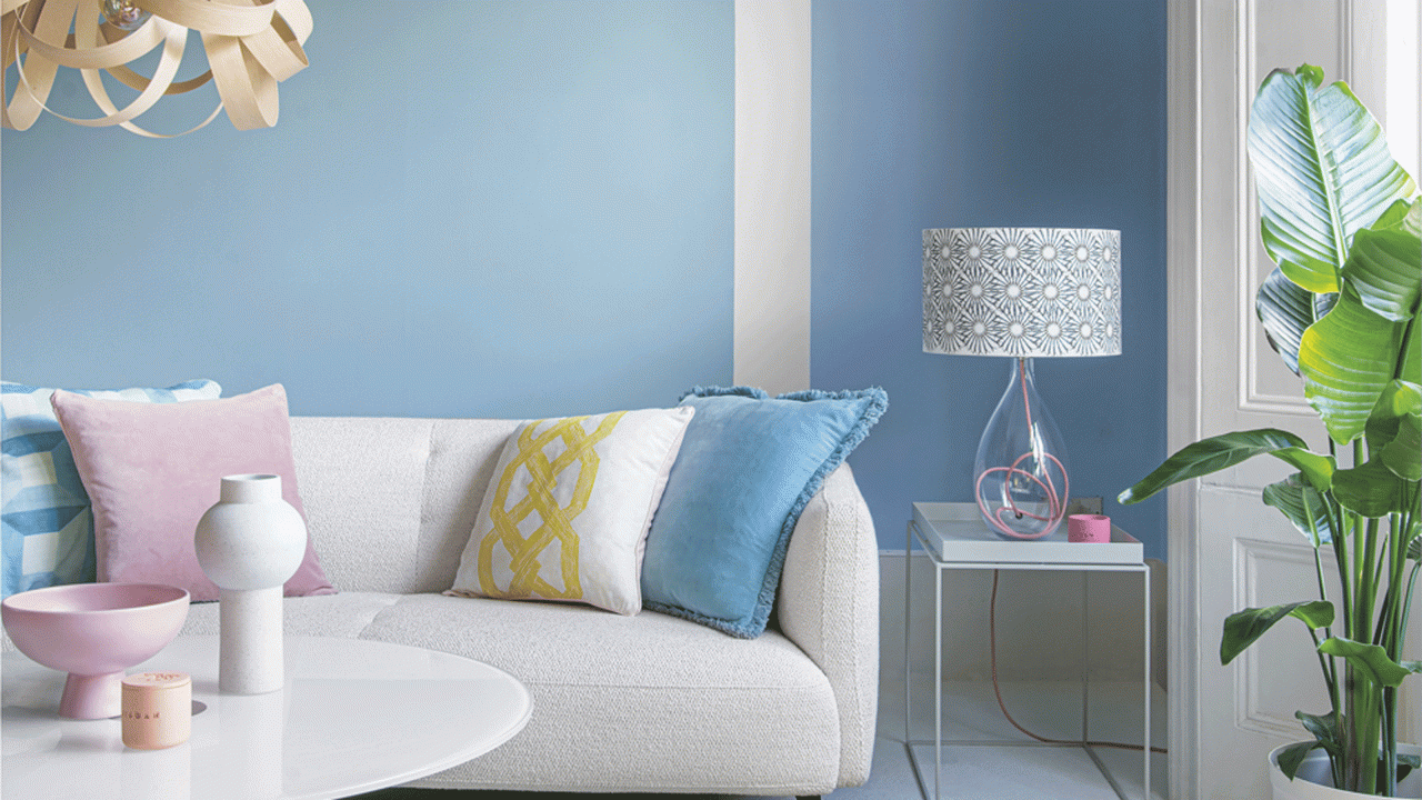 living room with blue wall white sofa with designed cushions and white round table