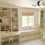 A window seat above storage drawers, with open shelves and a built-in desk alongside.